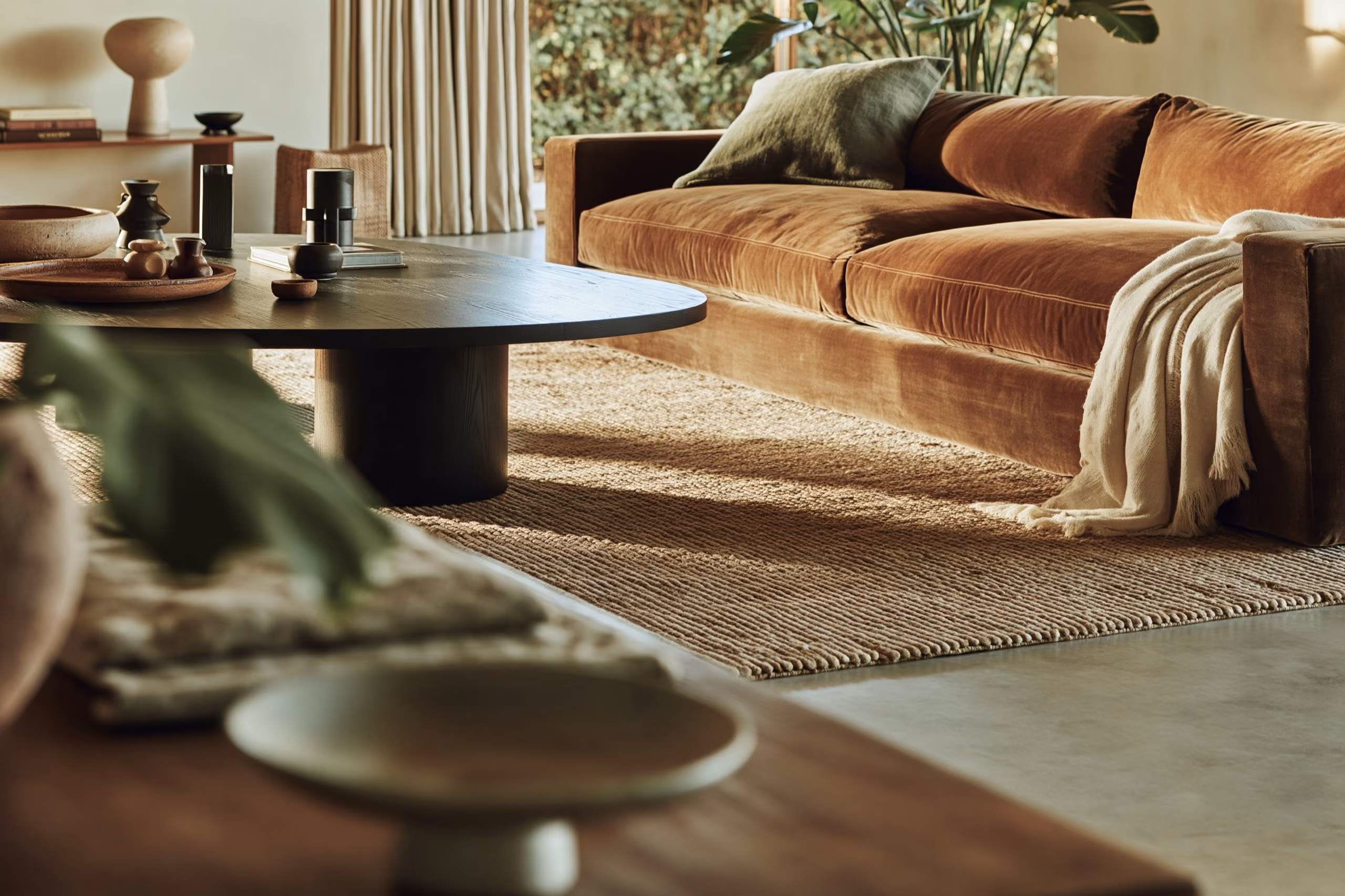Editorial-modern living room with a rust velvet sofa and jute rug — the kind of finished $60K room this piece runs through three fee models.
